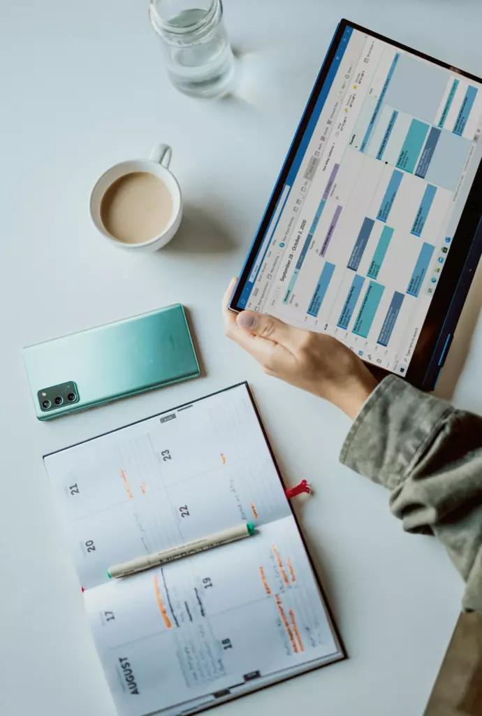 Un calendrier sur une tablette, à côté d'un agenda papier et d'un café